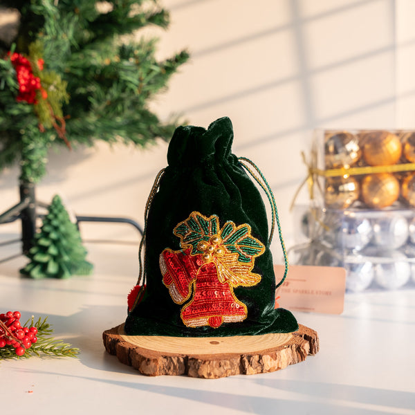 Decorative green velvet bag with embroidered design, Christmas tree and decorations in the background.

